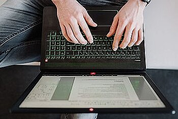 Zwei Hände auf Laptoptastatur.